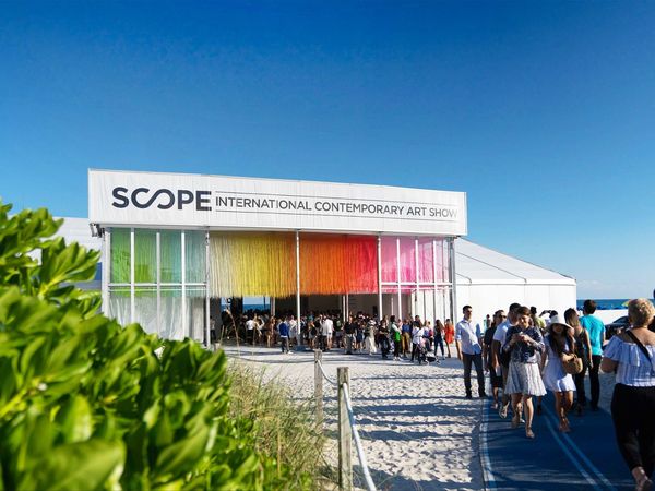Visitors on the boardwalk outside a SCOPE Art Show pavilion on the beach