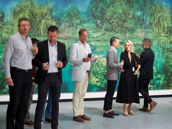 Guests in conversation in front of a large landscape painting