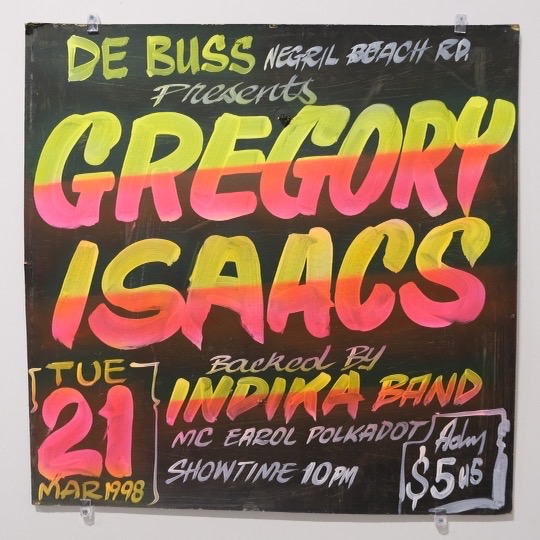 A Gregory Isaacs sign in pink, yellow and green on black