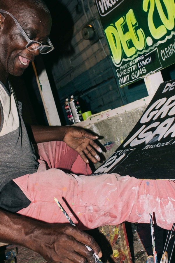Nurse, in glasses, painting a sign in his workshop