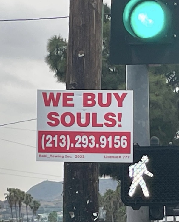 A WE BUY SOULS! sign beside a pedestrian crossing signal
