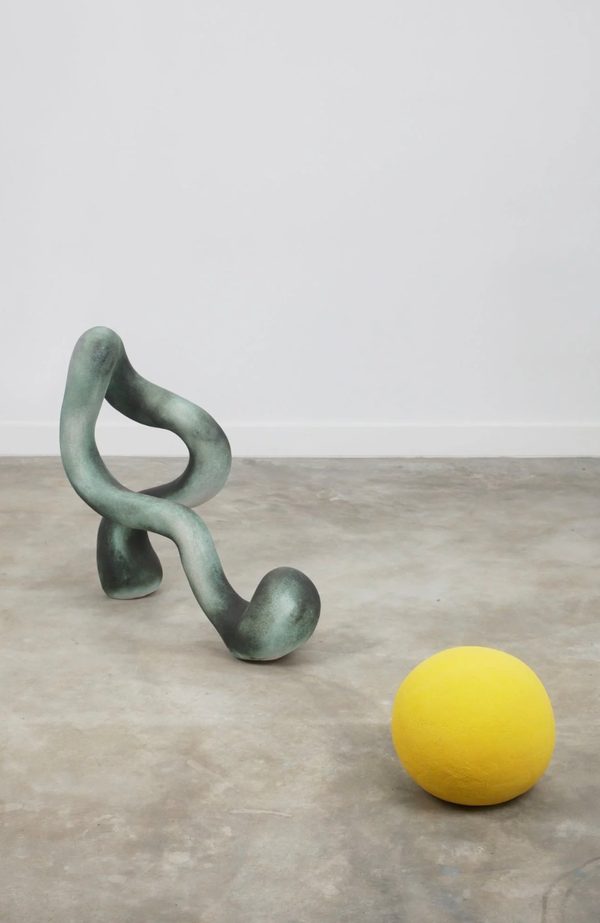 Willie by Pilar Wiley: a grey-green looping ceramic form and a yellow ball on a concrete floor